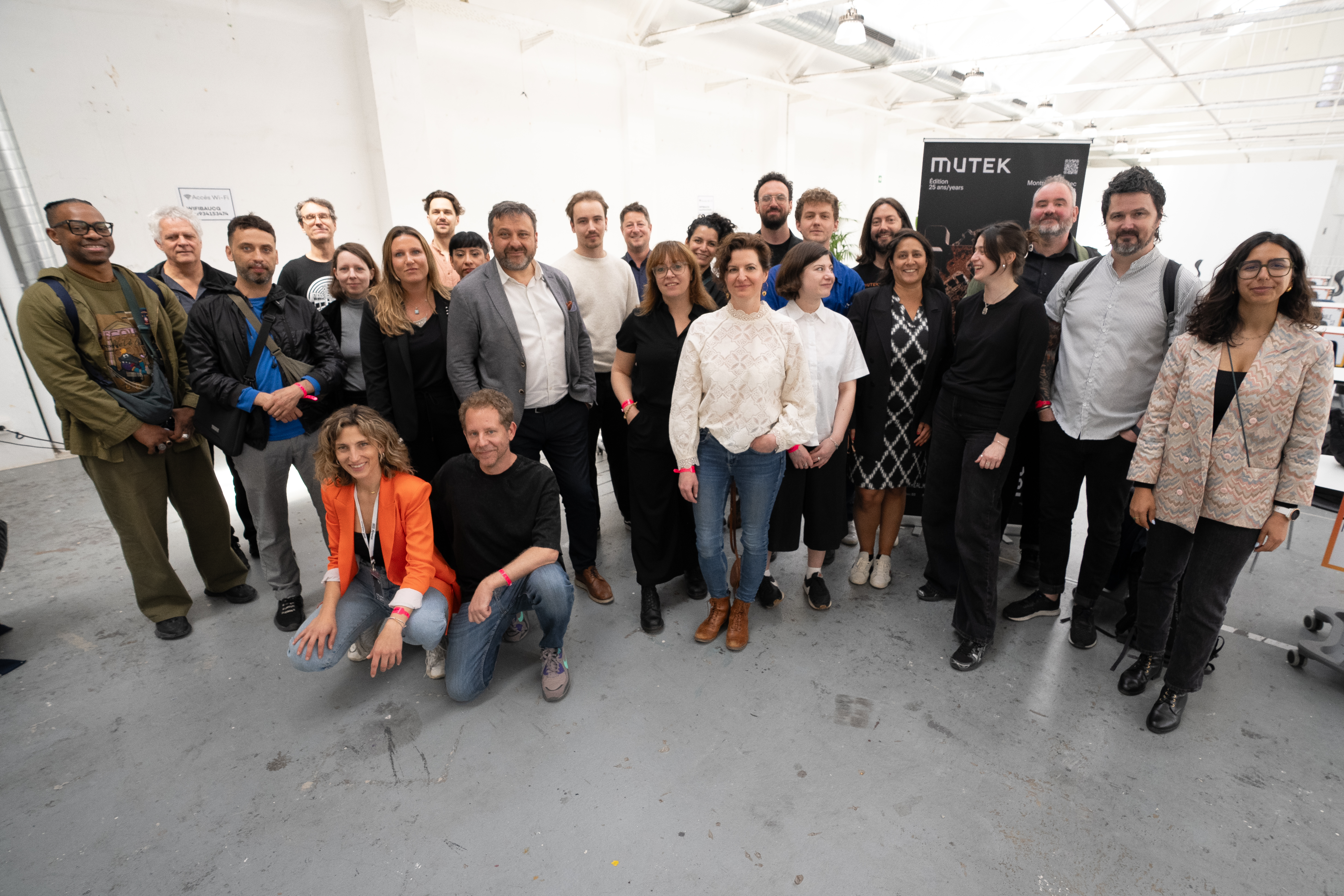 un groupe de personnes posant dans un espace blanc au plancher gris