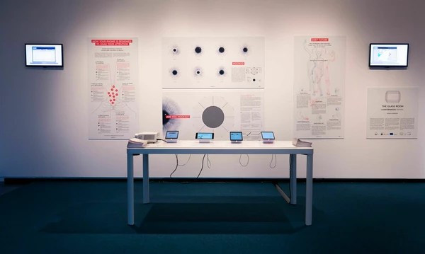 Une salle d'exposition montant plusieurs écrans sur une table et des symboles imprimés sur des affiches au mur.